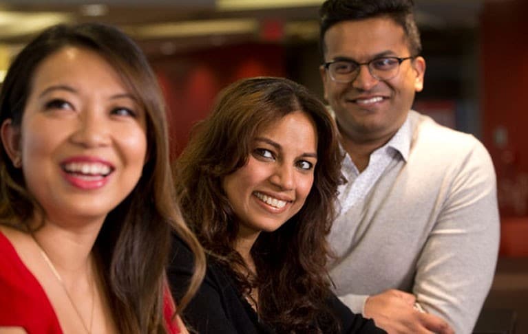 Trois personnes qui sourient dans un bureau