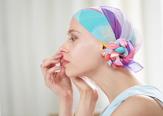 A woman going through cancer treatment putting on false eyelashes