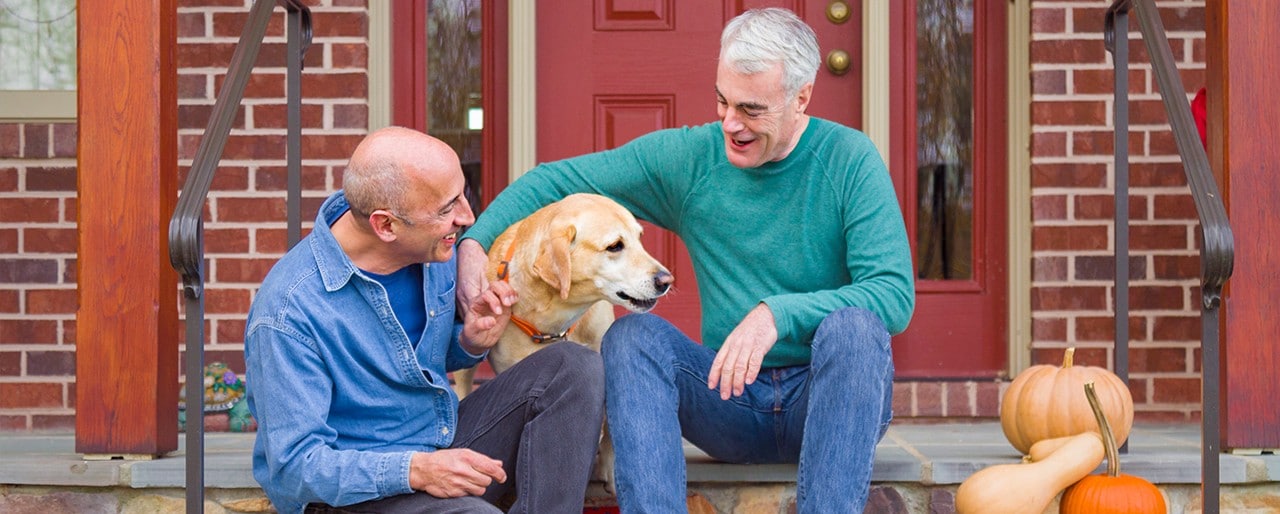 A couple sit on their porch with their dog.