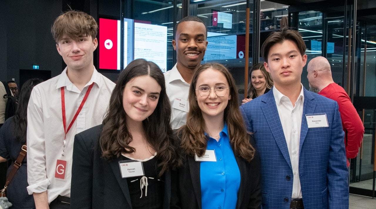 Five students with name tags stand together at a networking event.
