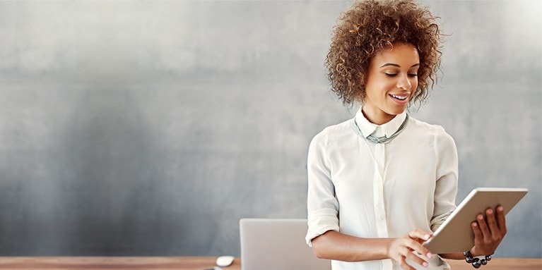 Standing woman looks at a tablet she is holding