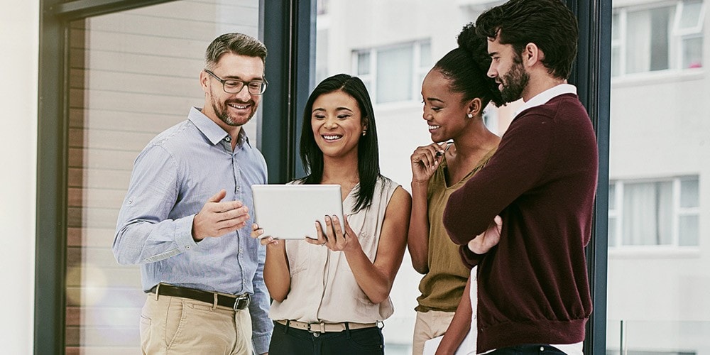 Happy group of employees looking at a tablet.