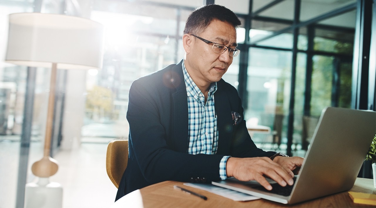 A man typing on his laptop in an office