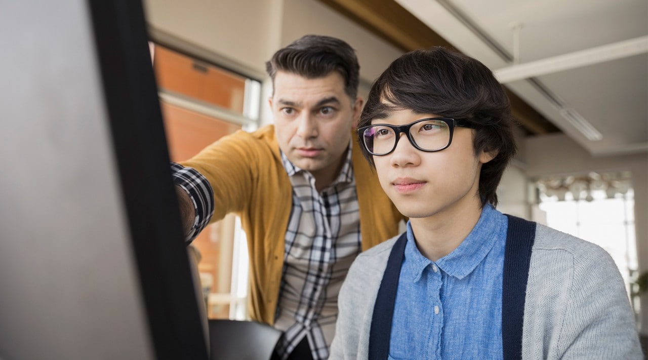 A father helping his son with financial planning on his computer