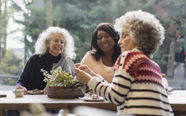 Three older women chat over breakfast.