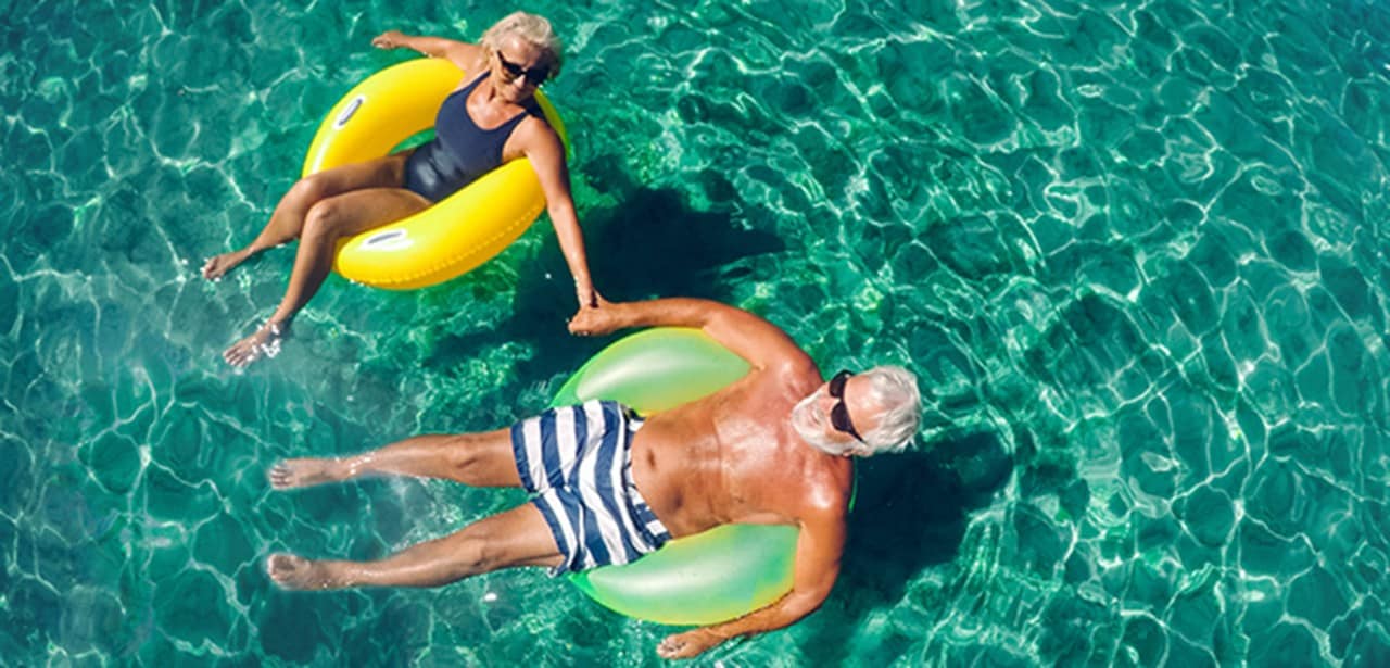 An older couple floating on inner tubes.