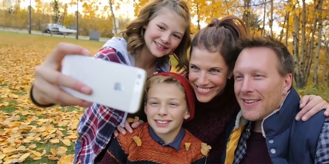 Une famille de 4 personnes prend un égoportrait dans un parc
