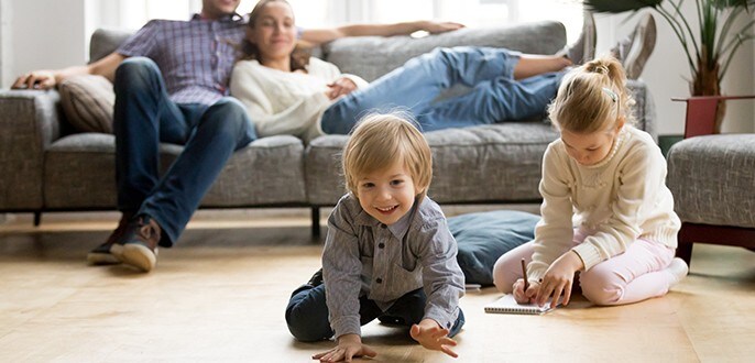 Un couple relaxe sur un canapé pendant que leurs enfants jouent par terre
