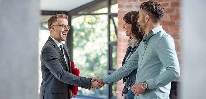 A real estate agent greeting a couple