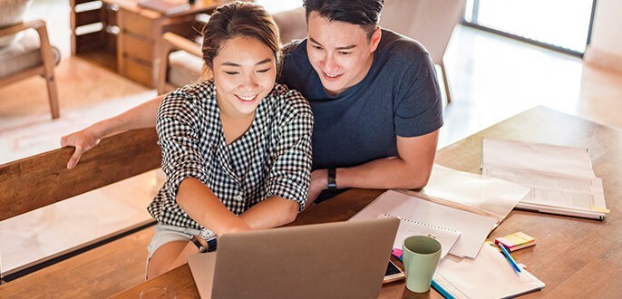 Un couple utilise un ordinateur portable et regarde des documents