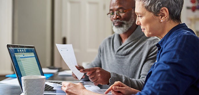 Un couple d’âge mûr regardent leurs finances sur un ordinateur portable