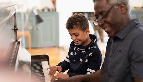 A grandpa giving his grandson a piano lesson