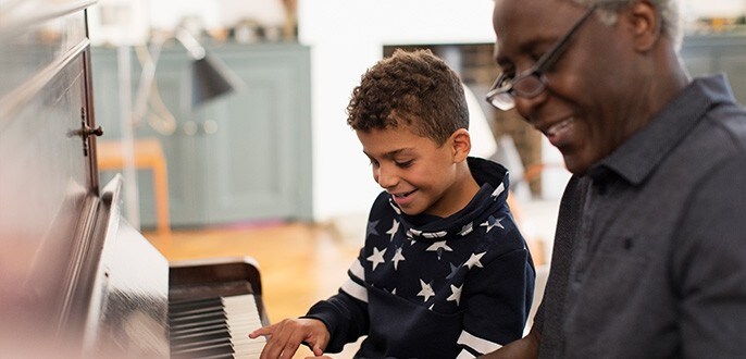 A grandpa giving his grandson a piano lesson