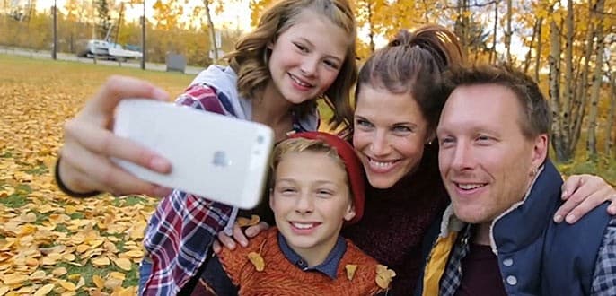 A family of 4 taking a selfie in a park