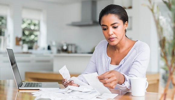 A woman seated at a desk with her laptop and receipts