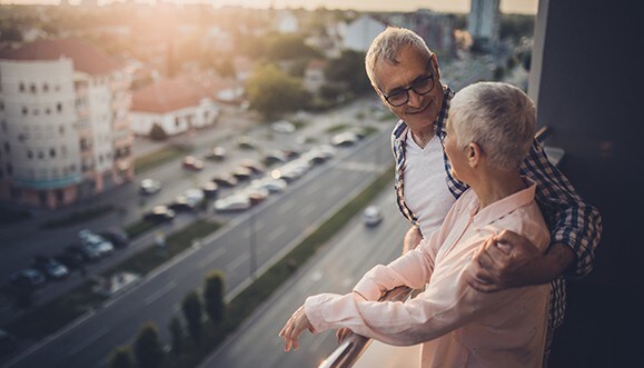 Un couple de retraités admire la vue depuis le balcon de leur condo