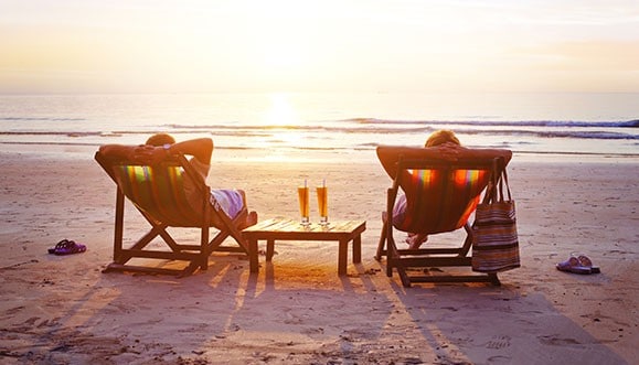 A couple having cocktails in lawn chairs at the beach