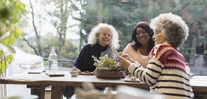 Trois femmes discutent assises à une table.