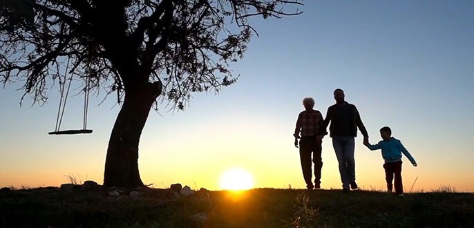 a couple and their child walking through a park at sunset