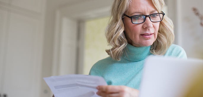 a woman going through documents while using her laptop