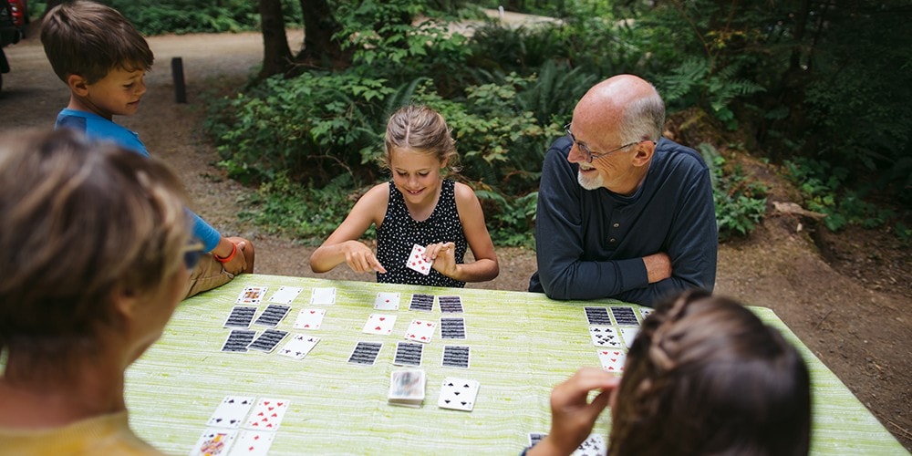 A man plays a game of cards with his grandchildren.