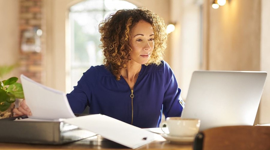 Person sits at desk with laptop, talking on the phone and smiling.