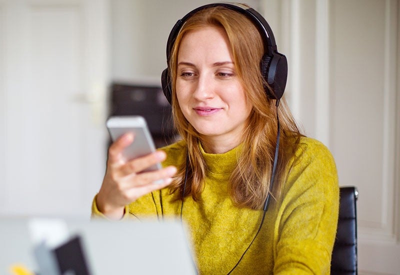 A young woman using her smartphone with headphones on