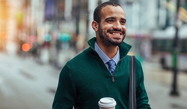 A well-dressed young man on the street, holding his coffee