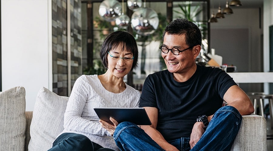 Couple on a couch looking at a tablet together