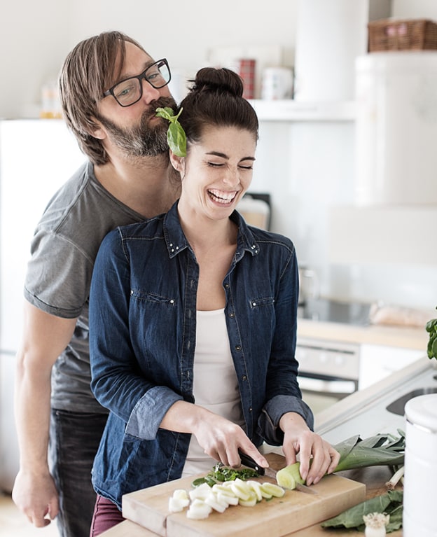 A happy couple prepare a meal at home
