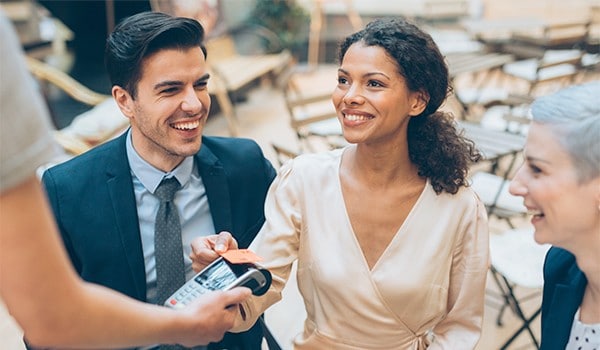 A woman at lunch with her coworkers paying by tapping her card