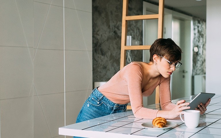 Une femme, dans sa cuisine, consulte sa tablette