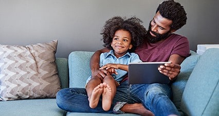  Father and son playing with a tablet together on the couch