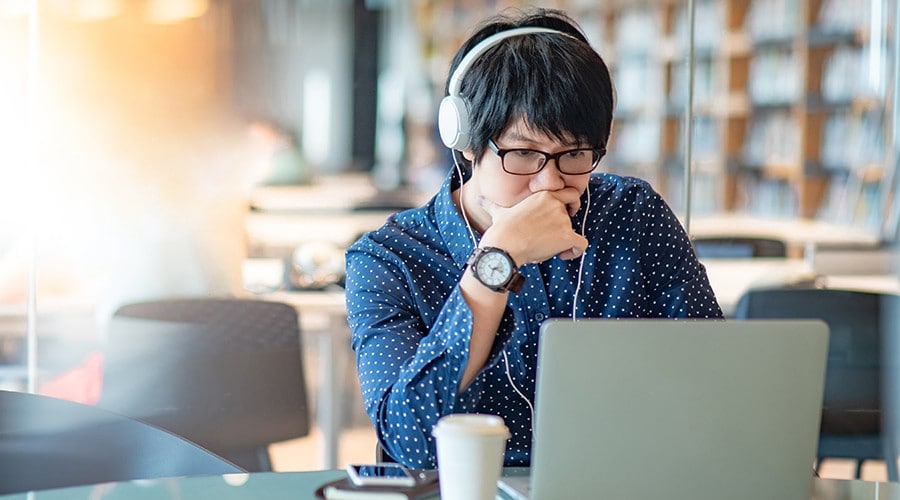 Student with headphones using a laptop in a library