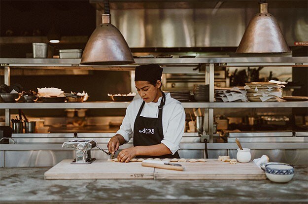 Une chef fait des pâtes dans la cuisine de Acre Baja.