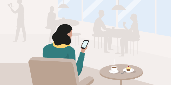  Une femme assise dans un café regarde son téléphone intelligent
