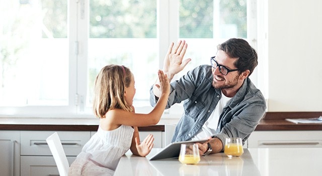 A father reviewing information with his daughter and giving her a high-five.