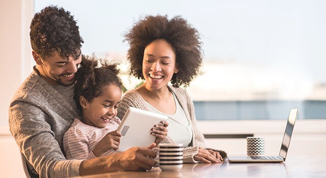 Un père et une mère joue avec leur fille et sont assis à la table.