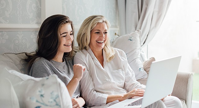 A smiling mother and daughter looking at a laptop.