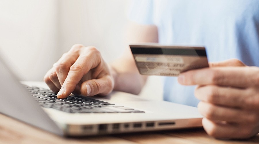 A man typing in his credit card information on his laptop.