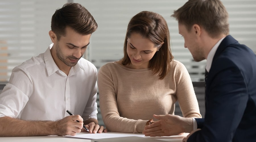 Young couple meeting with an advisor and signing documents.